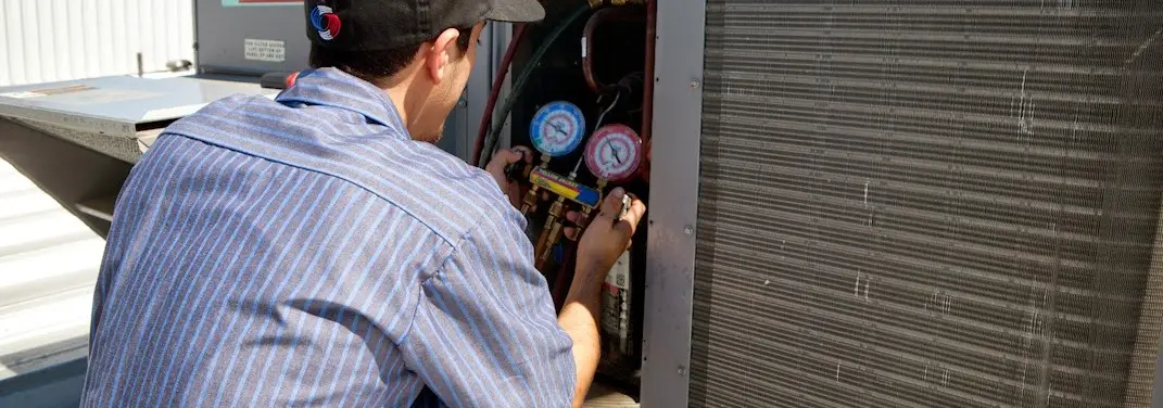 HVAC technician servicing a condenser unit in Elizabeth City